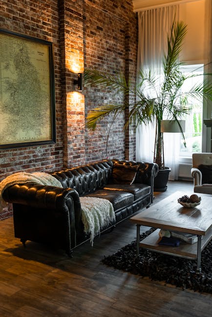 Stylish industrial-style living room featuring a leather sofa, rustic brick wall, and indoor plants.